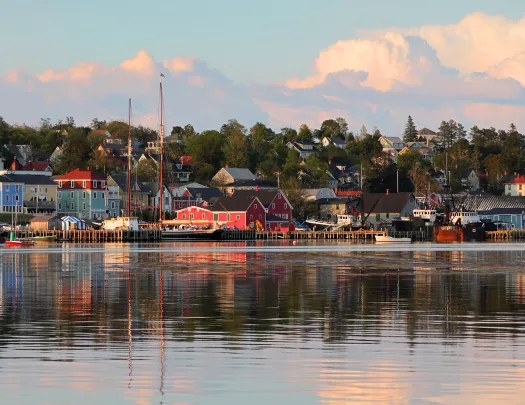 Wide shot of seaside town at sunset, vibrant red houses scattered throughout.