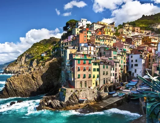 Wide shot of Cinque Terre houses, small pier and ocean down below.