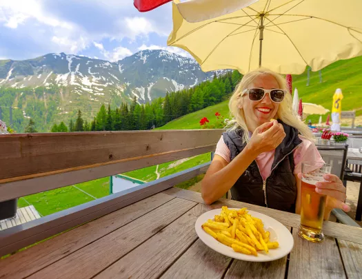 Woman eating french fries on restaurant patio.