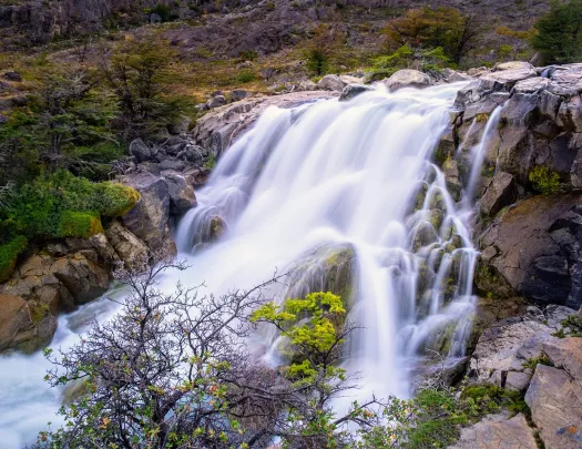 Shot of flowing waterfall, trees, river.