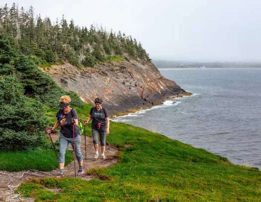 Two guests walking alongside coastal cliff.