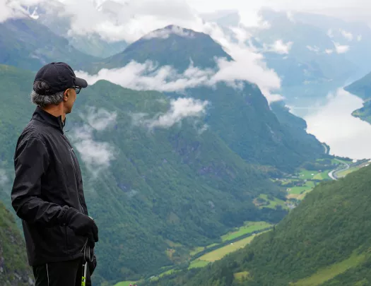 Solo hiker looking out over a lush green valley in Norway