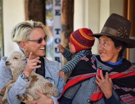 Guest holding baby sheep, with two locals.