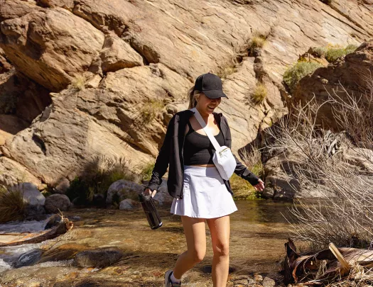 Guest walking on desert rocks, rocky hill in background.