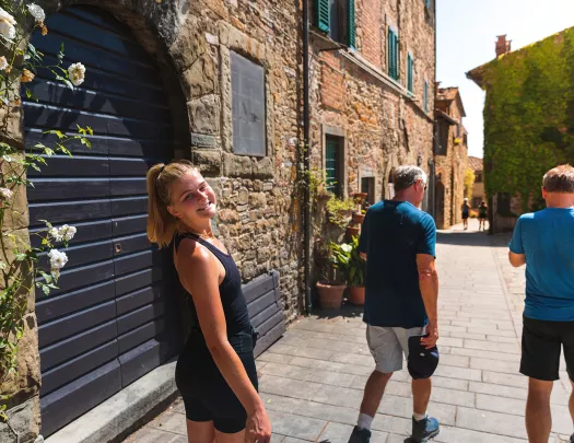 Three guests walking down brick road, one smiling at camera amidst storefronts.