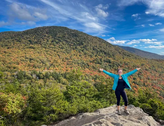 Guest gesturing to vast forest landscape, arms outstretched. 