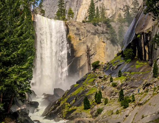 Shot of waterfall, craggy riverbed in foreground.