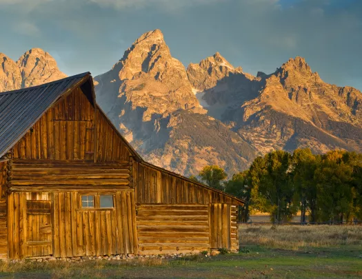 Wooden cabin with rocky mountains in background