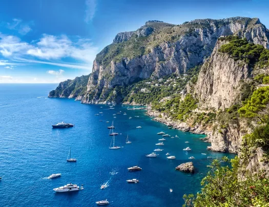 Wide shot of Amalfi Coast, boats dotting the crystal blue water.