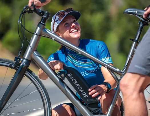 Backroads leader assisting cyclist with e-bike.