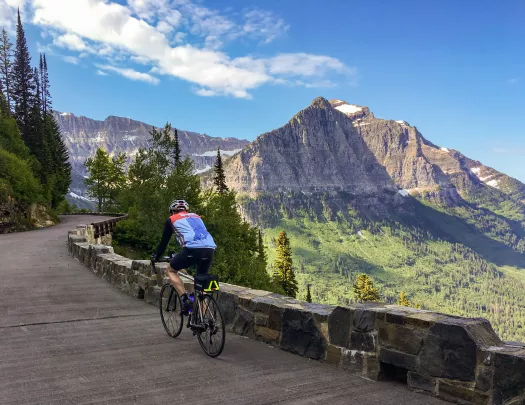 Man riding a bike on a windy road with a mountain in the distance