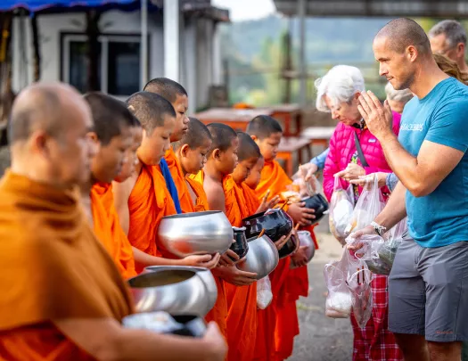 Group of people praying in front of monks with orange robes