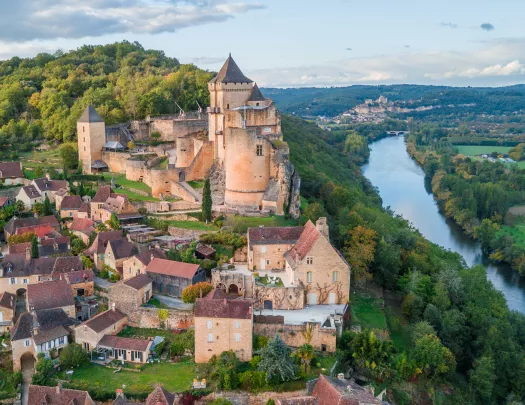 stone buildings surrounded by trees along a river
