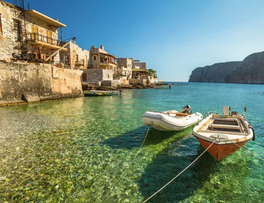 Two small boats tied to a dock with rustic buildings in the background