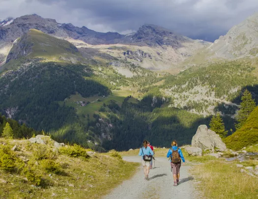 Three people descending a gravel trail on a mountain