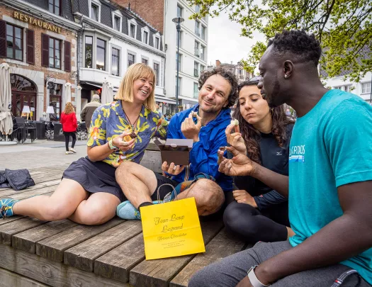 Two men and two women enjoy pastries on a bench