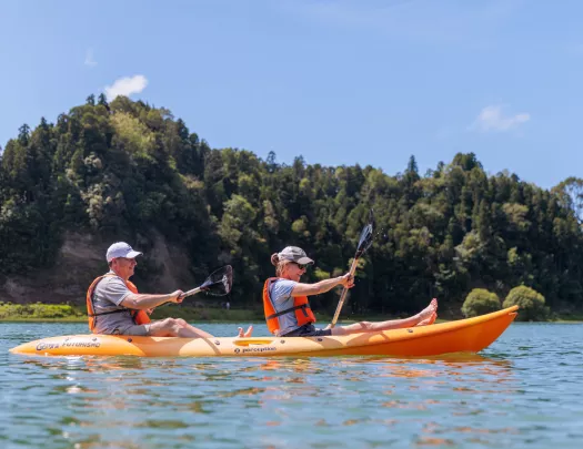 Man and woman inside of a kayak, paddling in the middle of a lake