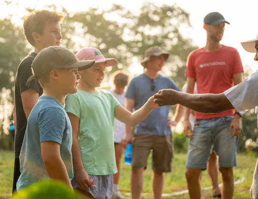Man handing a flower to two kids