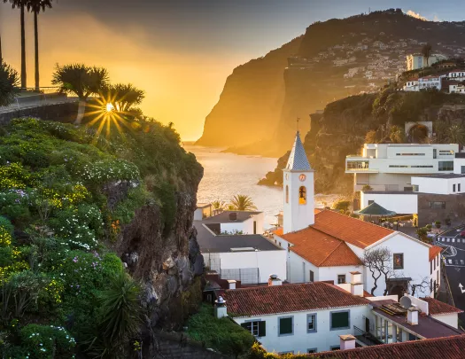 Sunset hitting a small town, filled with white and red buildings on cliffs