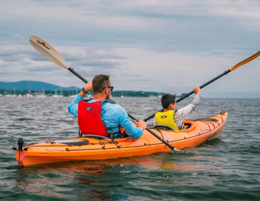 Man and son paddling inside of an orange kayak