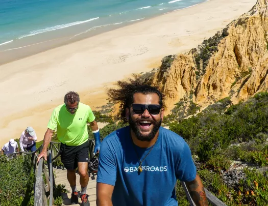 Man with blue shirt climbing up a flight of stairs on the beach
