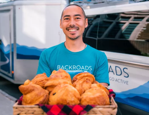 Man holding large basket of croissants