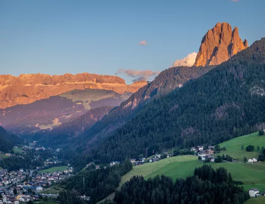 View of large hills covered in trees, with tall mountains in the distance