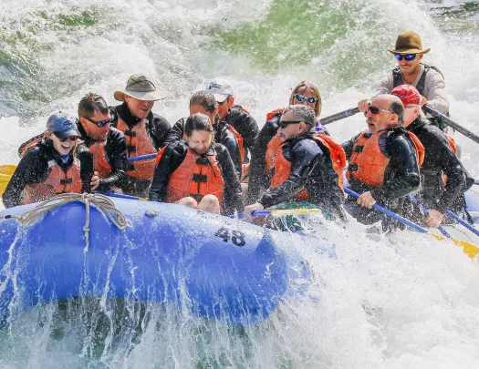 Group of men and women splashed during white water rafting