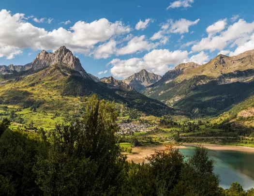 green mountains and lakes below a blue sky with white fluffy clouds