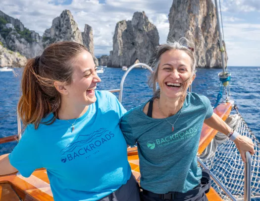 Two women on a boat, smiling while holding onto railings
