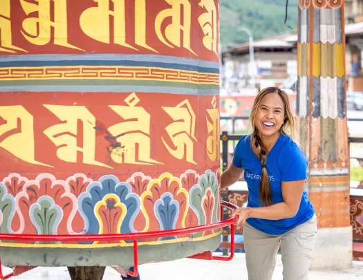 Woman smiling while holding a giant bell in a temple