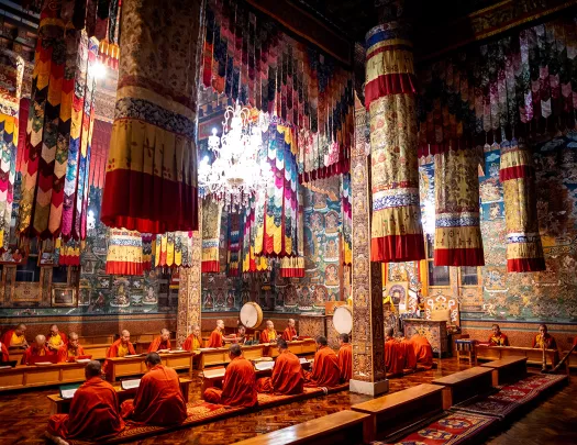 Monks sitting on the ground in the middle of a temply