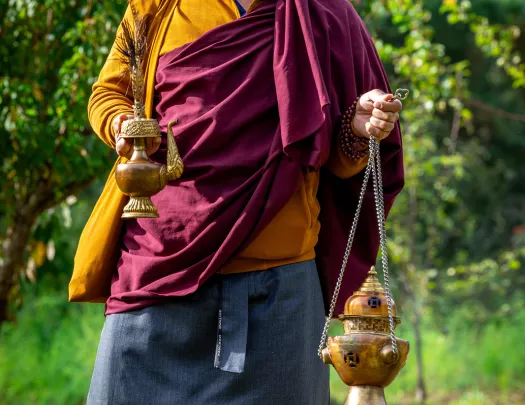 Monk smiling while holding onto bronze items