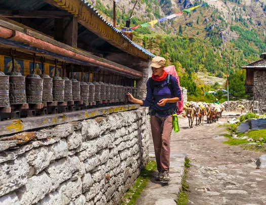 Woman walking along brick wall touching metal cans