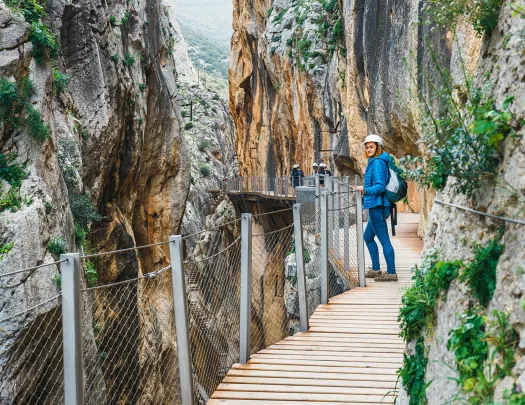 Woman standing on a wooden bridge, between two large cliffs