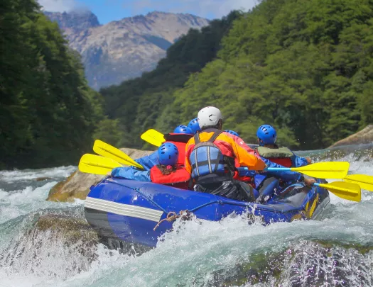 Group of people on a blue raft, paddling through an active river