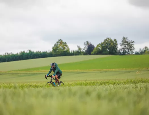 Man riding a bike on a road next to an empty valley of grass