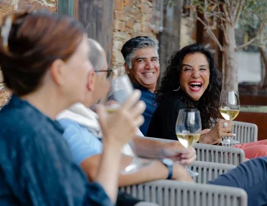 Group of people smiling and laughing while holding wine glasses