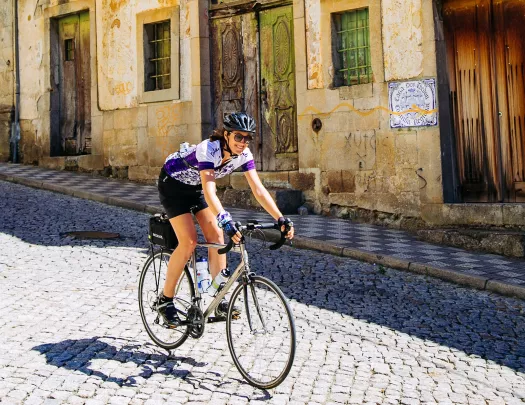 Woman smiling while riding a bike down a road in a town