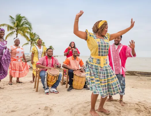 Two men playing large drums with a group of women dancing