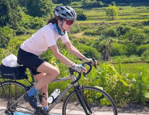 Woman riding bike on a path with large forest in the back