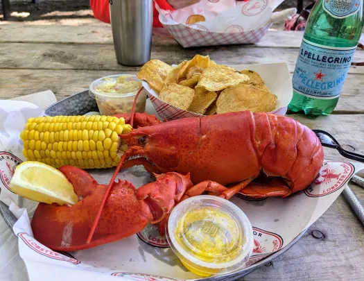 Plate with a boiled lobster, a half of corn and a plate of chips