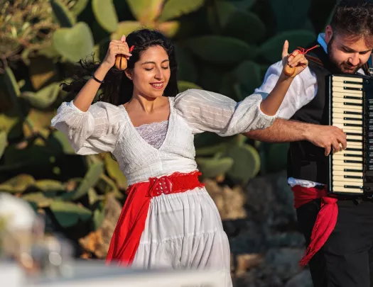Woman in a white dress, dancing with a man playing the accordion to her left