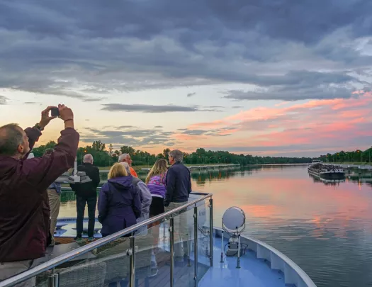 Group of people on a glass ledge looking at a sunset