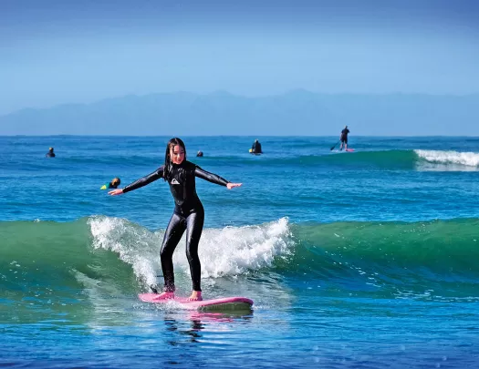 Girl standing on a pink surfboard in the ocean
