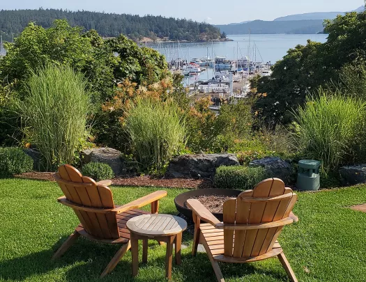 Two wooden chairs in an outdoor garden, overlooking boats and a large lake