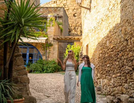 Two women smiling while walking through a stone alleyway