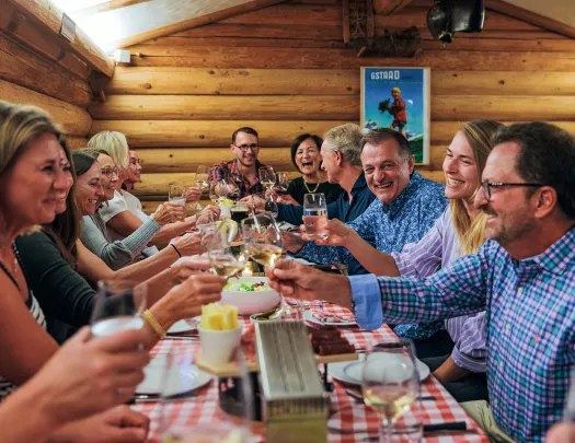 Wooden cabin restaurant with a group of people lifting up their glasses of wine