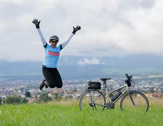 Woman jumping with her arms open, and a bike on the right