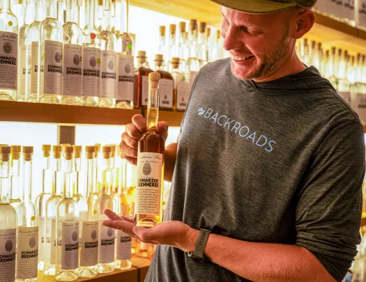 Man smiling while holding up a skinny bottle of alcohol